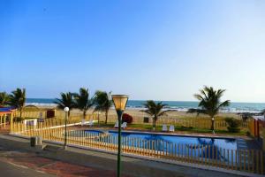 una piscina con recinzione e palme e la spiaggia di Ecusuites Playas two beds Fantasía 1 - a 45MinGye a Playas