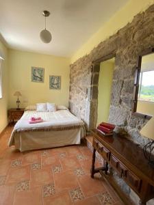 1 dormitorio con cama y pared de piedra en Casa Hortiñas en Chancelas