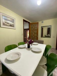una mesa blanca con sillas verdes, platos y flores. en Casa Hortiñas en Chancelas