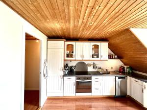 托爾斯港的住宿－Apartment in central Torshavn，厨房配有白色橱柜和木制天花板