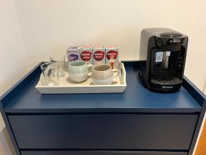 a blue counter with a tray with cups and a coffee maker at Lavender Retreat in Wrexham