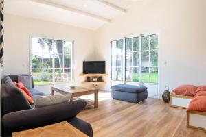 ein Wohnzimmer mit Sofa und Fernseher in der Unterkunft "NOLA" Charmante Villa contemporaine et spacieuse in La Flotte