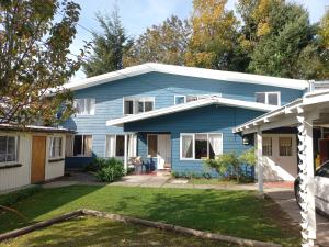 a blue house with a yard at Hostería Alemana in Villarrica