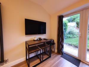 a living room with a television on a wall at Old School House Studio in Stetchworth