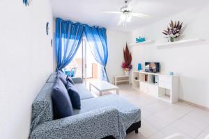 sala de estar con sofá azul y ventana en Las Galletas House, en Las Galletas