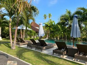 a pool with chairs and umbrellas next to a resort at Bingin Family Bungalow in Uluwatu