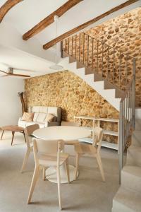 a dining room with a table and chairs and a stone wall at Casa Cresolera in Villalonga