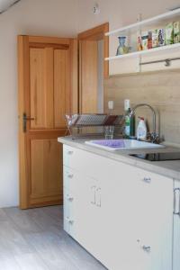 eine Küche mit weißen Schränken, einem Waschbecken und einer Tür in der Unterkunft Apartmán Zahrádka in Česká Lípa