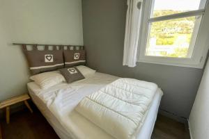 een slaapkamer met een bed met witte lakens en een raam bij Bright 50 M With Balcony And View On The Valley in Briançon