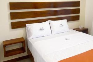 a bed with two white pillows and a wooden headboard at La Posada de Mindo in Mindo