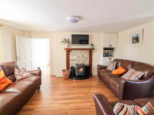 sala de estar con sofás de cuero y chimenea en Grange Farmhouse en Fethard on Sea