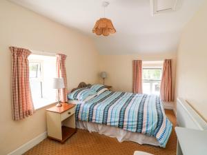 a bedroom with a bed and two windows at Grange Farmhouse in Fethard on Sea