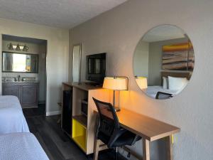 a hotel room with a desk and a mirror at Days Inn & Suites by Wyndham Dayton North in Dayton