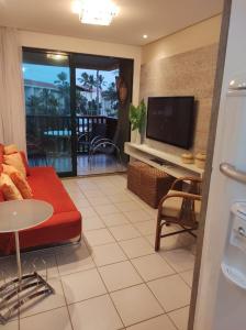 sala de estar con sofá rojo y TV de pantalla plana en Flat Experience Marulhos Resort, en Porto de Galinhas