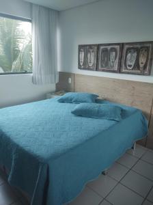 a bedroom with a bed with blue sheets and a window at Flat Experience Marulhos Resort in Porto De Galinhas