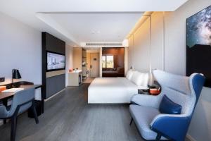 Pokój hotelowy z łóżkiem, biurkiem i krzesłami w obiekcie Atour Hotel Nanjing Xianlin Unviersity Town w mieście Nankin