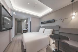 a bedroom with a white bed and a table at Atour Light Hotel Nantong Drum Plaza South Street in Nantong