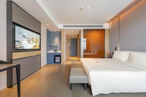 a bedroom with a large white bed and a flat screen tv at Atour Hotel Kunshan Baoyu Plaza North Changjiang Road in Kunshan