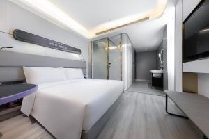 a bedroom with a large white bed and a bathroom at Atour Light Hotel Chengdu Wenjiang in Wenjiang