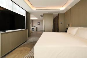 Schlafzimmer mit einem großen weißen Bett und einem Flachbild-TV in der Unterkunft Atour Hotel Wuhan Hankou Financial Center in Wuhan