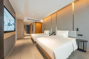 a hotel room with two beds and a flat screen tv at Atour Hotel Huai an Suning Plaza Dazhi Road in Huai'an