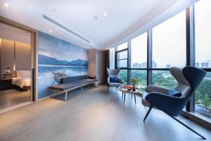 een woonkamer met uitzicht op het water en een slaapkamer bij Atour Hotel Meishan Government Affairs Center in Meishan