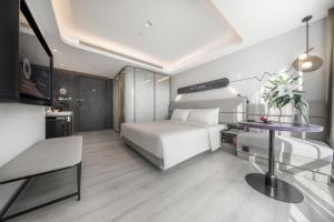 1 dormitorio con cama blanca y mesa en Atour Light Hotel Hefei Government Affairs Swan Lake, en Hefei