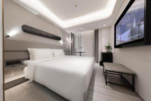 a bedroom with a white bed and a flat screen tv at Atour Light Hotel Hefei Government Affairs Swan Lake in Hefei