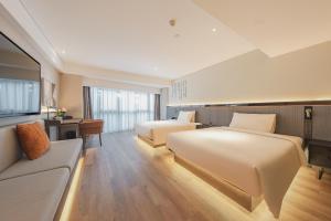 a hotel room with two beds and a couch at Atour S Hotel Wuxi Nanchang Street in Wuxi