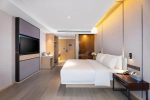 a hotel room with a large white bed and a television at Atour Hotel Hengyang South Mountain Hengshan Scenic Area in Nanyue
