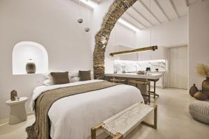 a white bedroom with a large bed and a table at Elaia Luxury Suites Mykonos in Mýkonos City