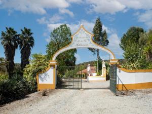 an entry gate to a house with palm trees at Idyllic Farmhouse in Montemor o Novo with Pool in Montemor-o-Novo