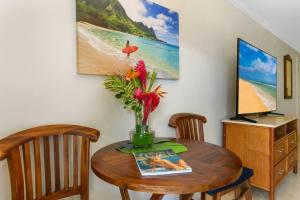 uma mesa de jantar com um vaso de flores em Islander Ocean Resort Condo # 166 em Kapaa