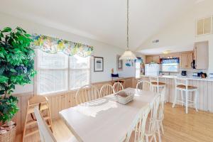 a kitchen and dining room with a white table and chairs at Charmed Life RO22 in Rodanthe