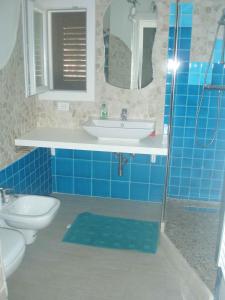 ein blau gefliestes Badezimmer mit Waschbecken und Toilette in der Unterkunft Holiday home in Orosei Nuoro Provinz 39543 in Orosei