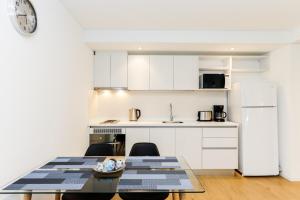 uma cozinha com armários brancos e uma mesa com cadeiras em Pacífico Apartamentos Terrazas em Ushuaia