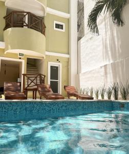 einen Pool mit Stühlen und ein Haus in der Unterkunft Rodina Boutique Hotel in Playa del Carmen