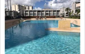 una gran piscina azul con edificios en el fondo en Isla Verde Beach Modern apartment, en San Juan