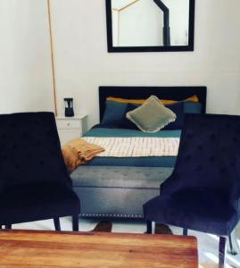 1 dormitorio con 1 cama y 2 sillas en The kauri Tree Pod - Off Grid Experience, en Levin