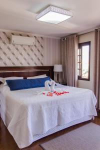 a bedroom with a white bed with roses on it at Pousada da Paz in Curitiba
