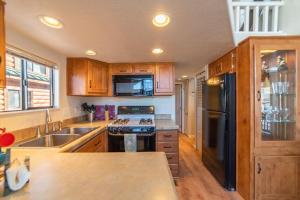 a kitchen with wooden cabinets and a black refrigerator at Enjoy the Tiny Home Experience as the Perfect Basecamp to the Rockies! The Northstar Cabin in Fairplay