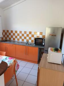 a kitchen with a sink and a refrigerator and a table at Residence Corail in Sainte-Rose