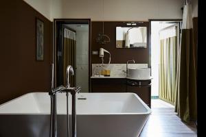 a bathroom with a tub, sink and mirror at Josh Hotel in Bangkok