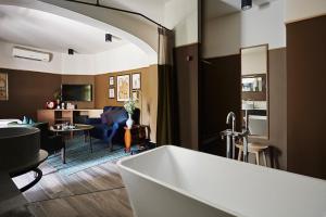 a bathroom with a bath tub and a living room at Josh Hotel in Bangkok