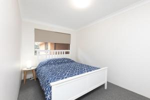 een witte slaapkamer met een bed en een raam bij Oceancrest 15 in Forster