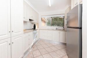 een keuken met witte kasten en een raam bij Oceancrest 15 in Forster +6 foto's