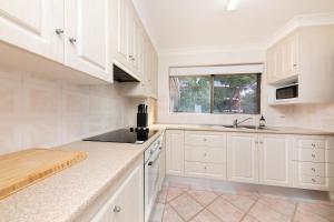 een witte keuken met witte kasten en een raam bij Oceancrest 15 in Forster