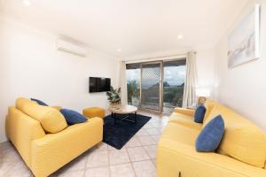 een woonkamer met twee gele banken en een tv bij Oceancrest 15 in Forster