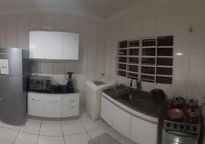 a white kitchen with a sink and a refrigerator at Casa incrível com 2 quartos e estacionamento incluso in Maringá +19 photos