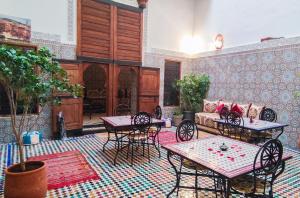a patio with tables and chairs and a couch at Riad Fes EL KAID in Fès